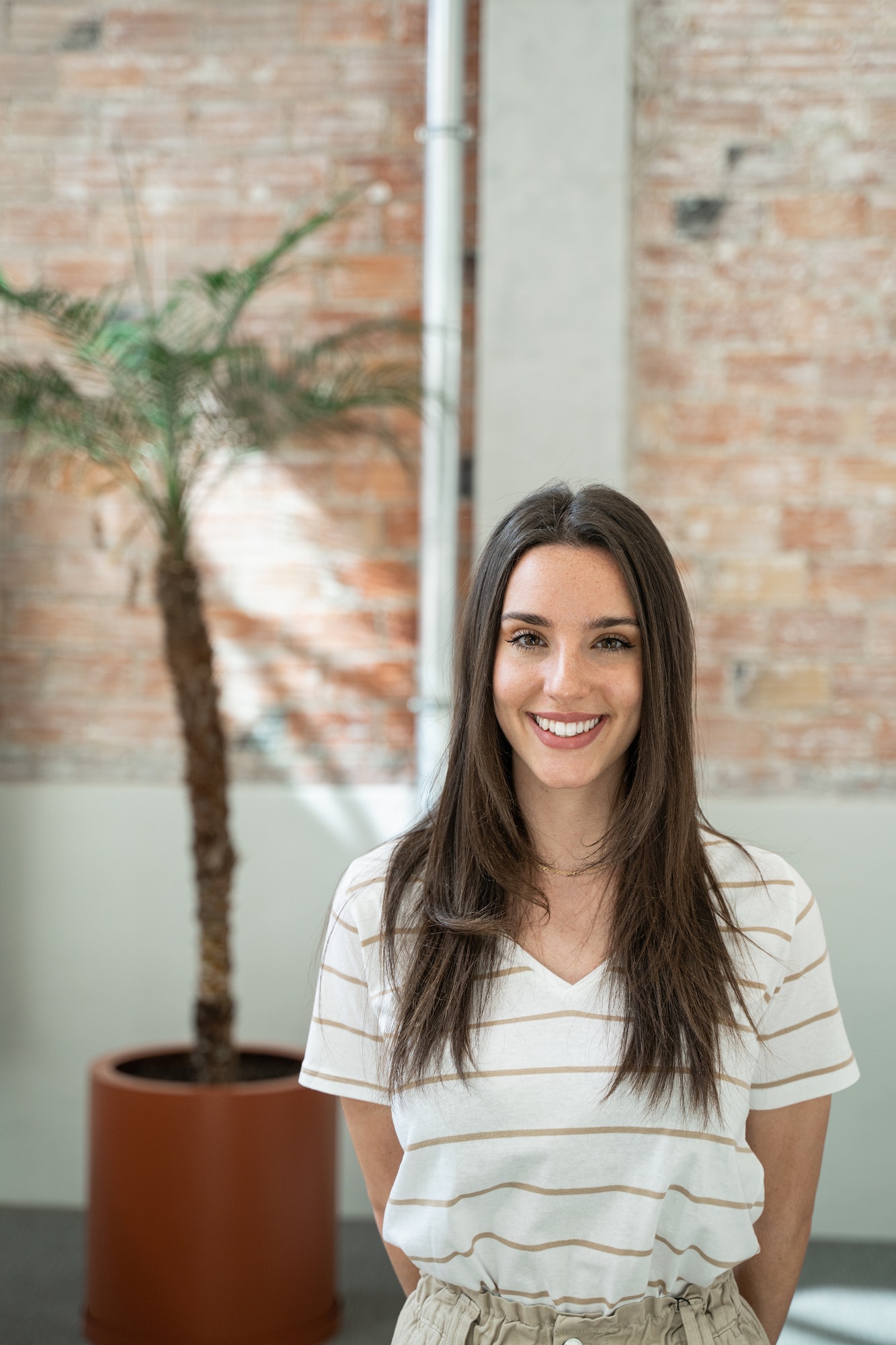 Portrait of young woman employee in a modern office with brick walls doing internship